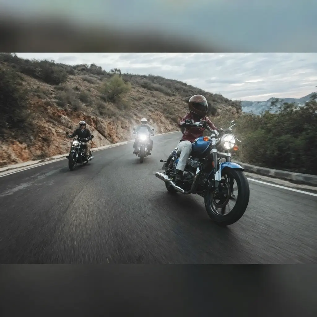Blaue Royal Enfield Super Meteor 650 mit Fahrer und geschlossenem Visier auf einer kurvigen Bergstraße vor zwei weiteren Motorrädern