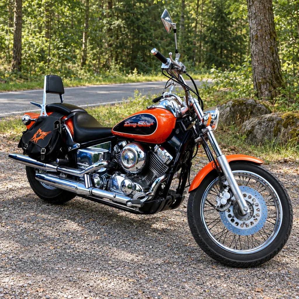 Orange-schwarze Yamaha XVS 650 Drag Star auf einem Waldparkplatz an einer ruhigen Landstraße